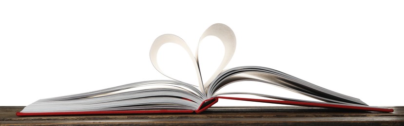 Photo of Open book with pages folded in heart on wooden table against white background