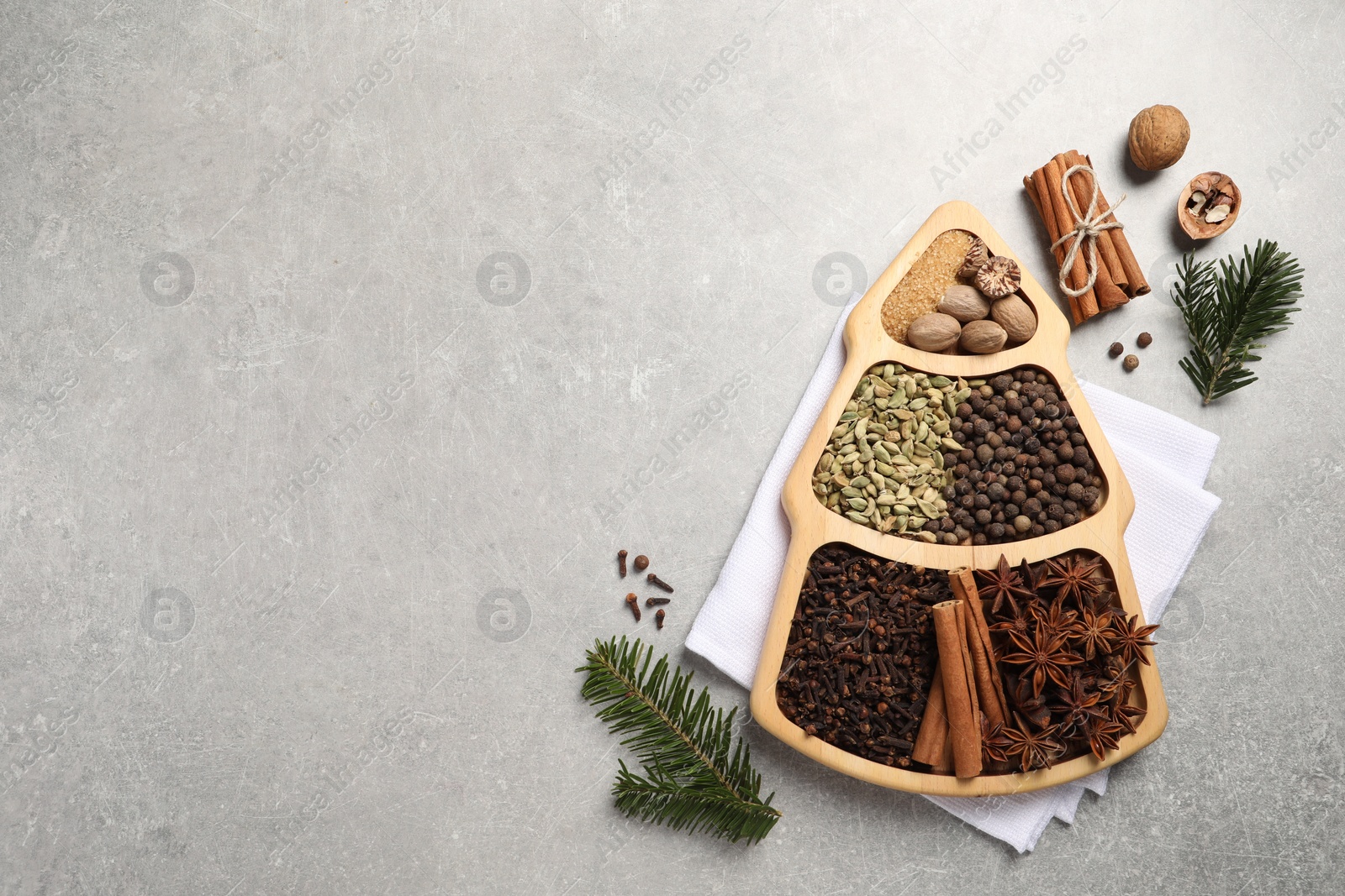 Photo of Different spices, nuts and fir branches on gray textured table, flat lay. Space for text