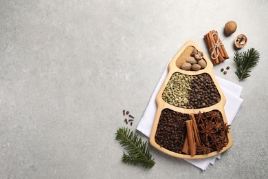 Photo of Different spices, nuts and fir branches on gray textured table, flat lay. Space for text