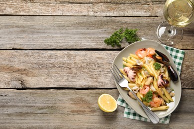 Delicious pasta with sea food served on wooden table, flat lay. Space for text