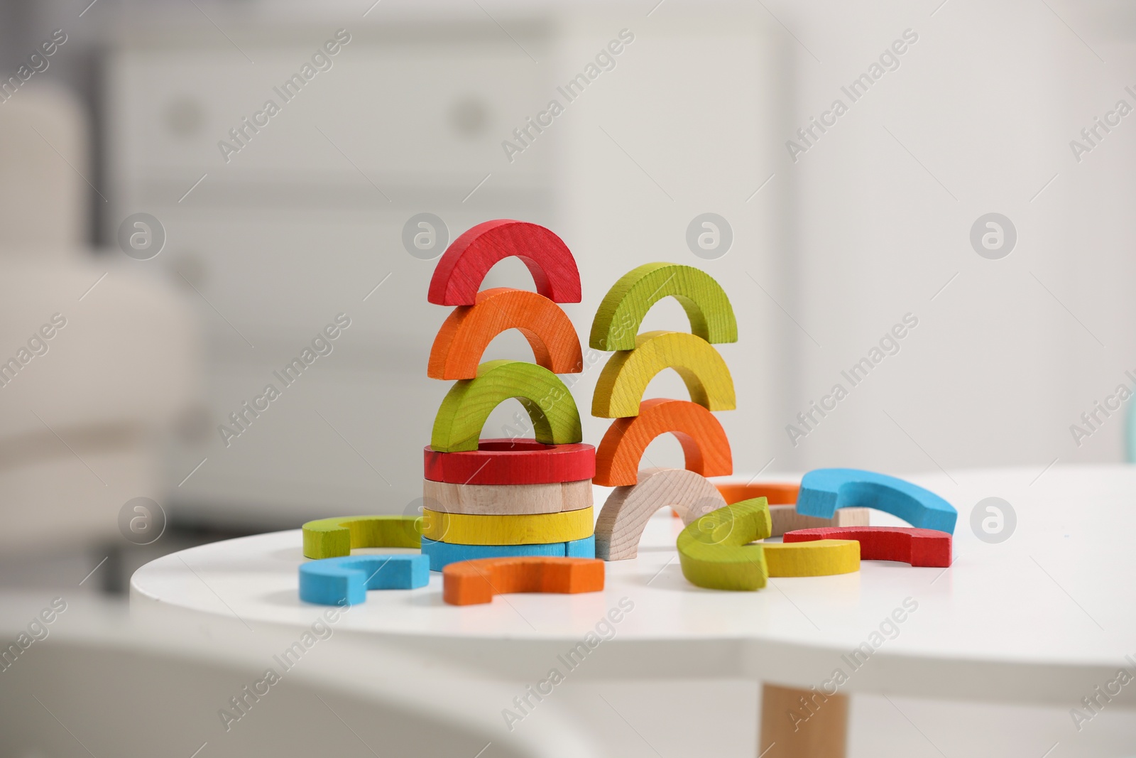 Photo of Colorful wooden pieces of playing set on white table indoors. Educational toy for motor skills development