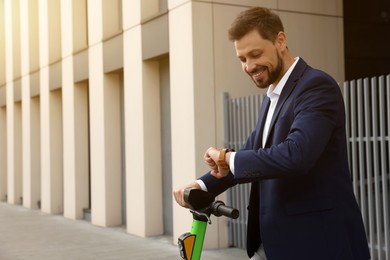 Photo of Businessman with modern kick scooter on city street, space for text