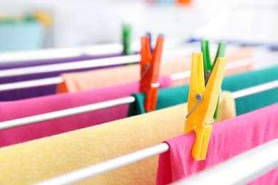 Photo of Clean laundry hanging on drying rack indoors, closeup