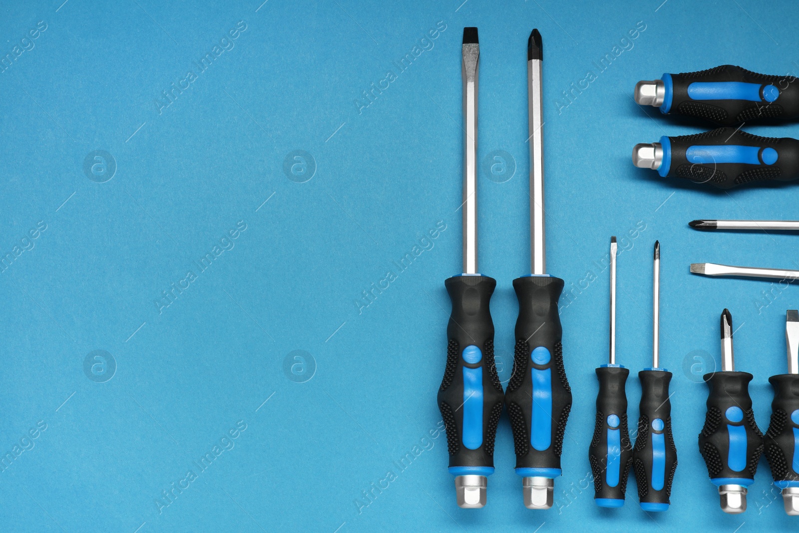 Photo of Set of screwdrivers on blue background, flat lay. Space for text