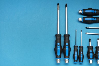Photo of Set of screwdrivers on blue background, flat lay. Space for text