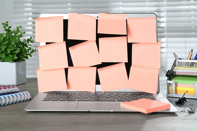Laptop with pink sticky notes on wooden table indoors