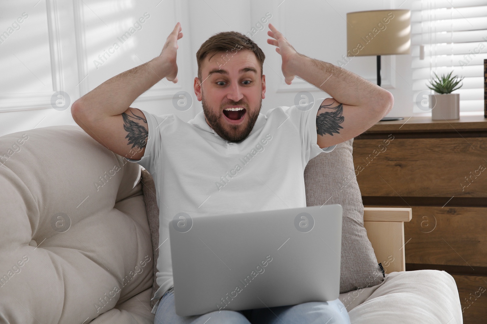 Photo of Emotional man participating in online auction using laptop at home