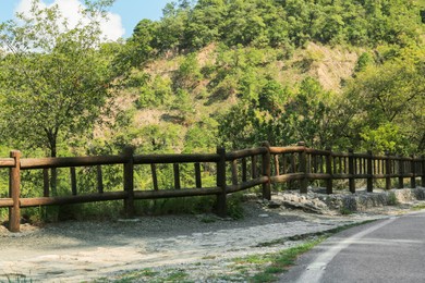 Photo of Wooden fence near asphalt road in mountains