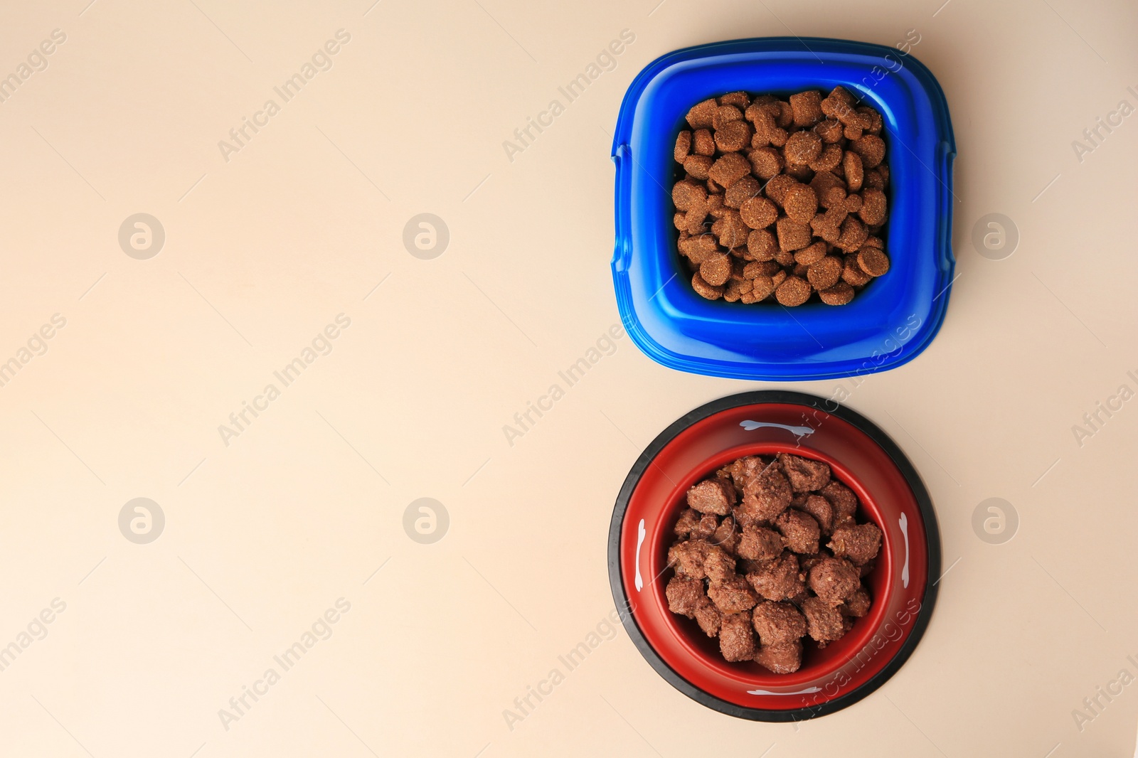 Photo of Dry and wet pet food in feeding bowls on beige background, flat lay. Space for text