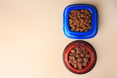 Dry and wet pet food in feeding bowls on beige background, flat lay. Space for text