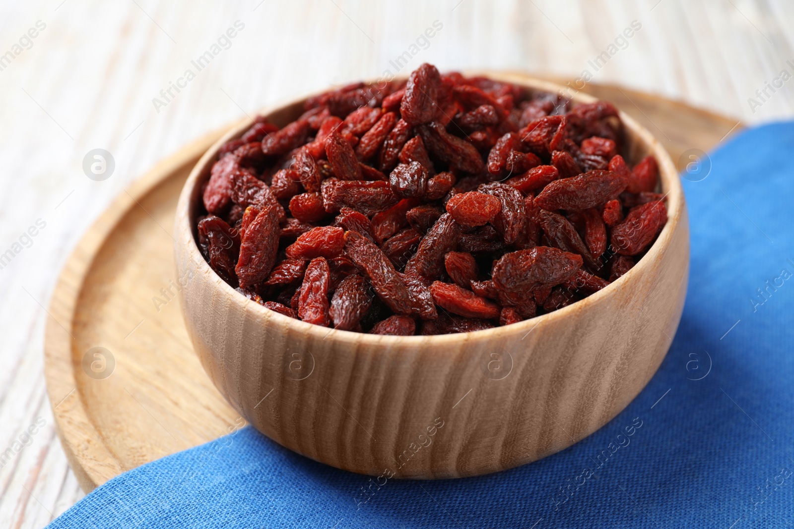 Photo of Dried goji berries in bowl on white wooden table, closeup