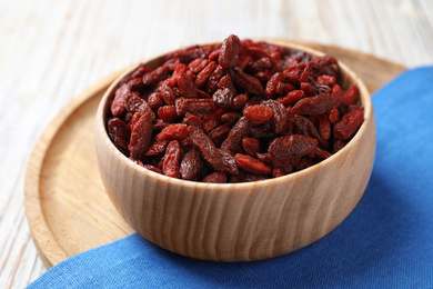 Photo of Dried goji berries in bowl on white wooden table, closeup