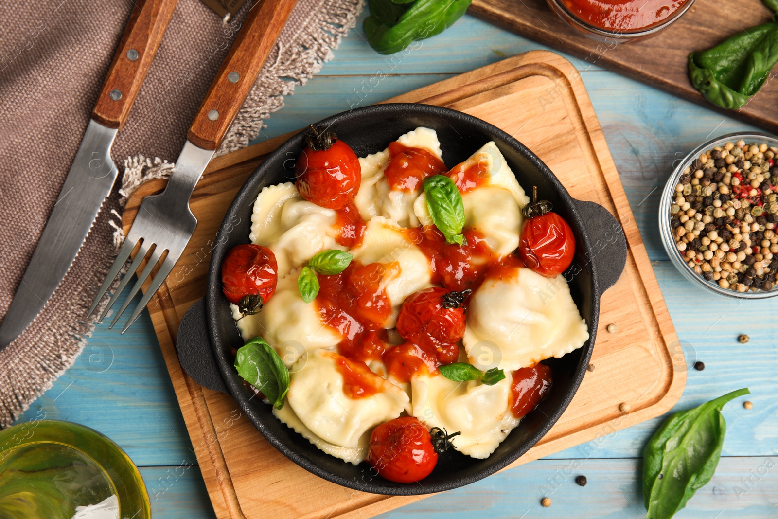 Photo of Tasty ravioli with tomato sauce served on blue wooden table, flat lay