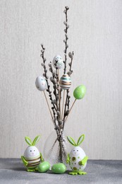Photo of Beautiful willow branches with painted eggs and Easter decor on light grey table
