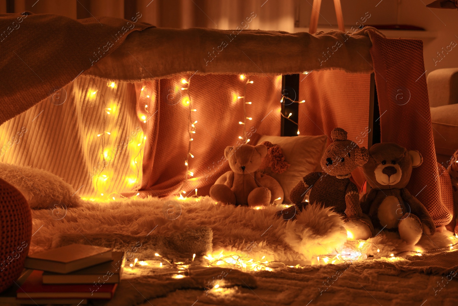 Photo of Beautiful play tent decorated with festive lights and toys at home