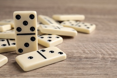 Photo of Domino tiles on wooden table, closeup. Space for text