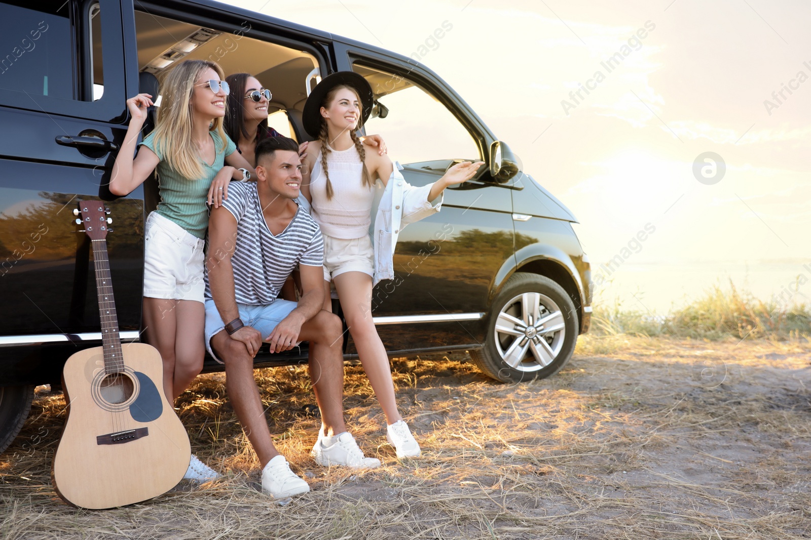 Photo of Happy friends near car outdoors. Summer trip