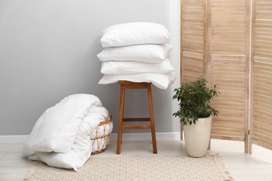 Photo of Soft pillows, duvet, chair and houseplant indoors