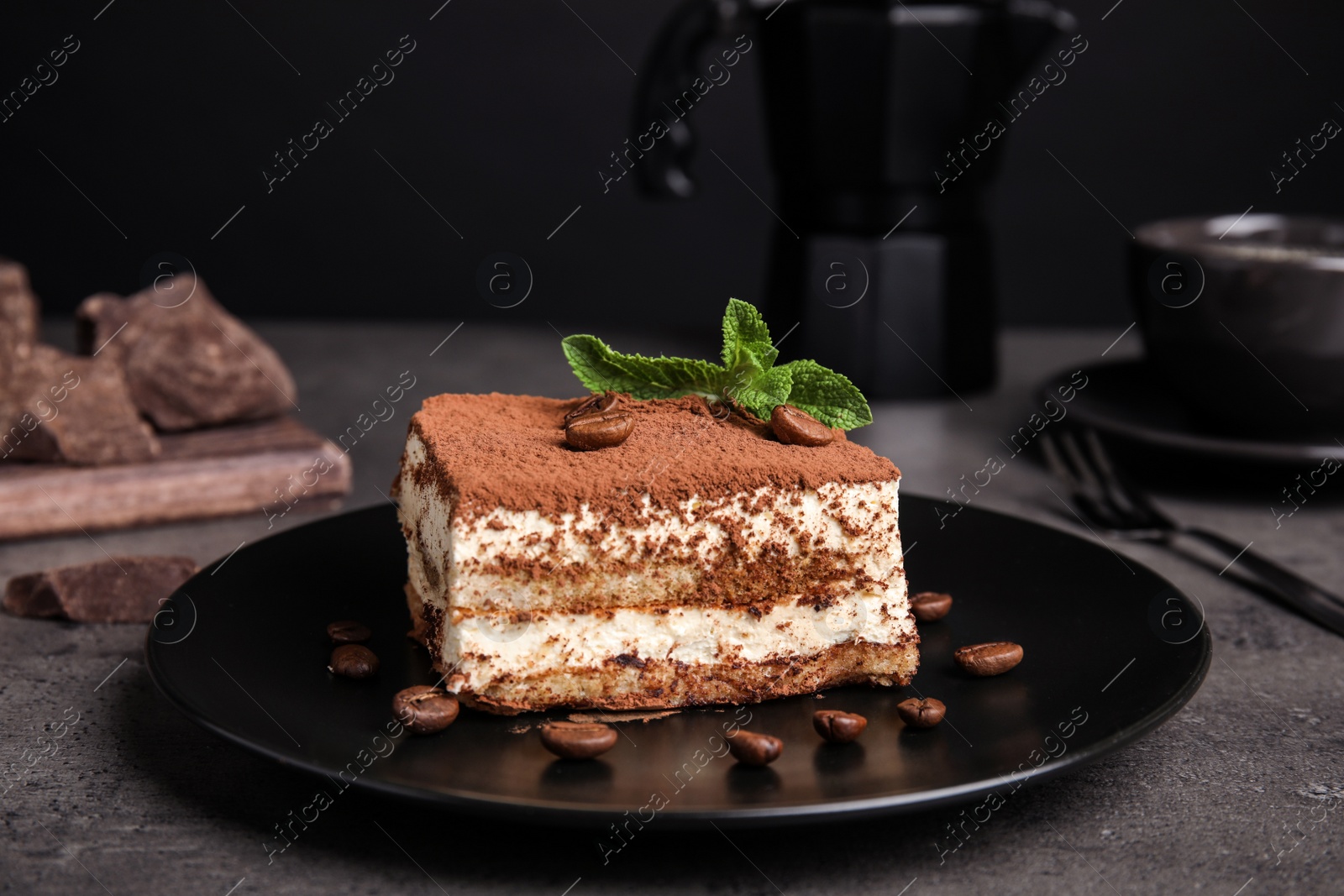 Photo of Composition with tiramisu cake on table against dark background