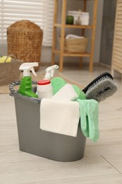 Photo of Different cleaning products in bucket on floor indoors