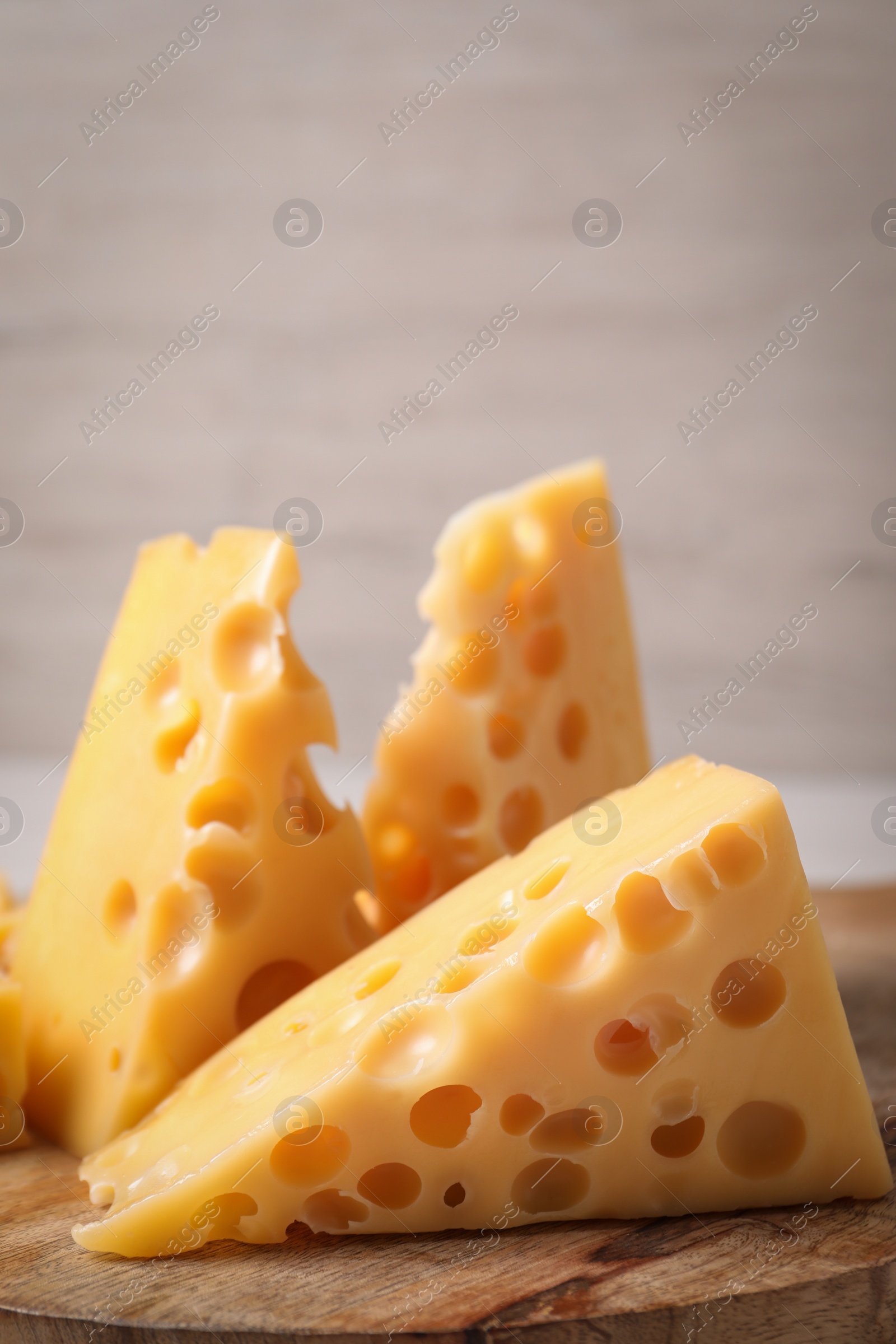 Photo of Pieces of delicious cheese on wooden board, closeup