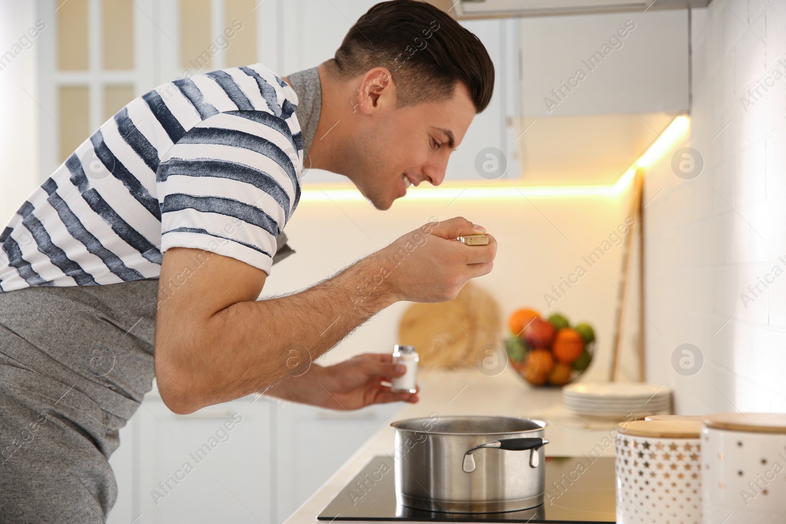 Photo of Handsome man cooking on stove in kitchen