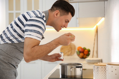 Handsome man cooking on stove in kitchen