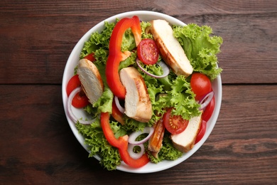 Photo of Delicious salad with chicken and vegetables on wooden table, top view