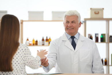 Pharmacist giving medicine to customer in drugstore