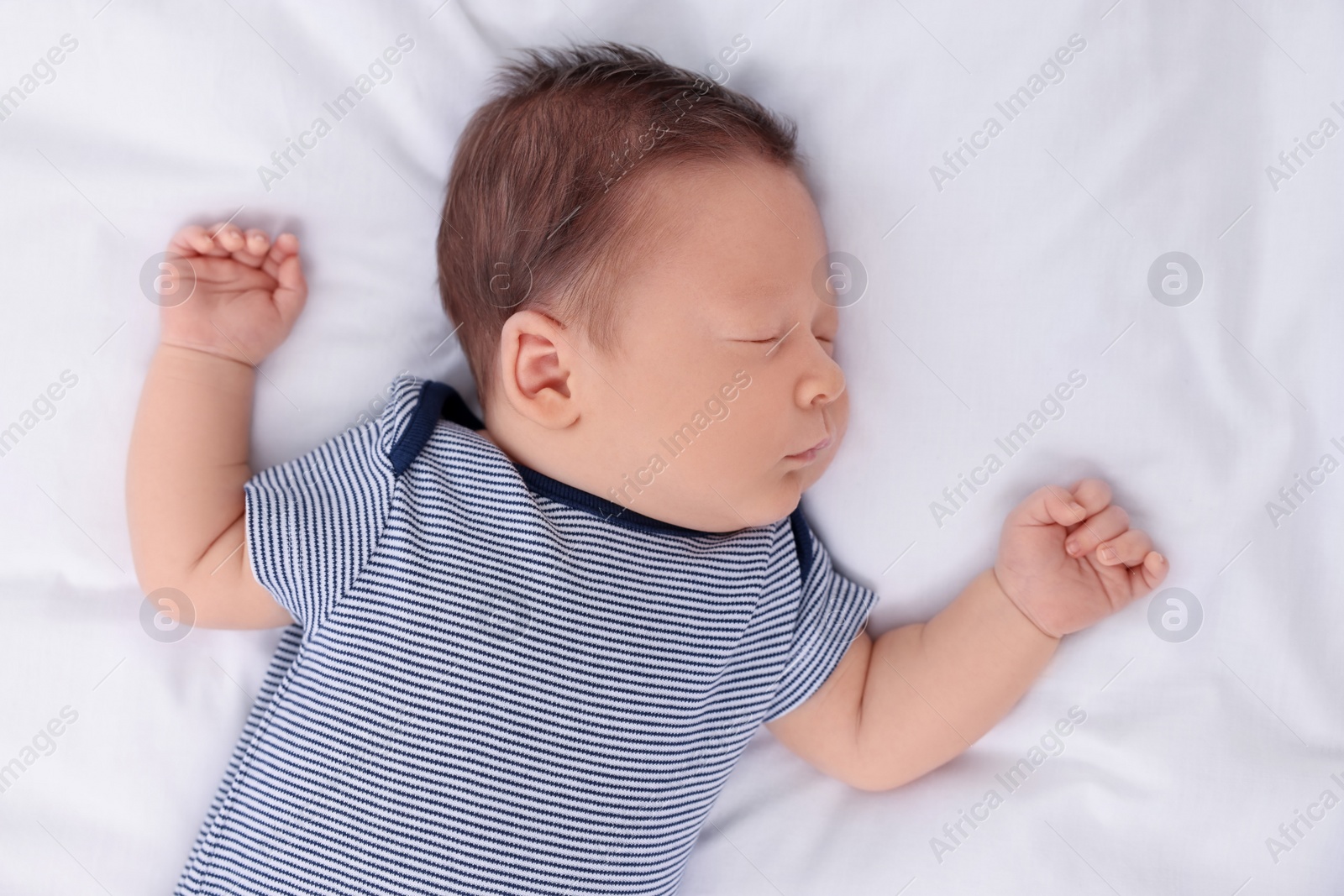 Photo of Cute newborn baby sleeping on white bed, top view