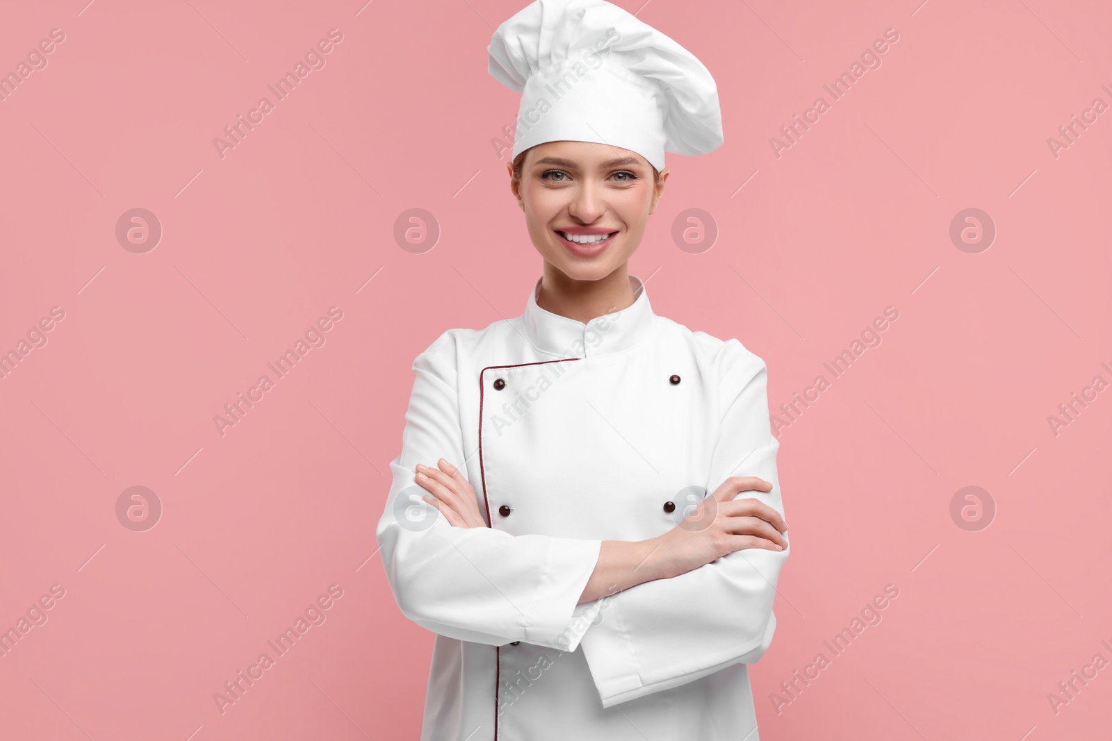Photo of Happy woman chef in uniform on pink background