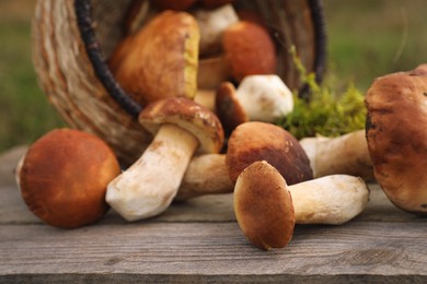 Photo of Fresh wild mushrooms on wooden table outdoors, closeup