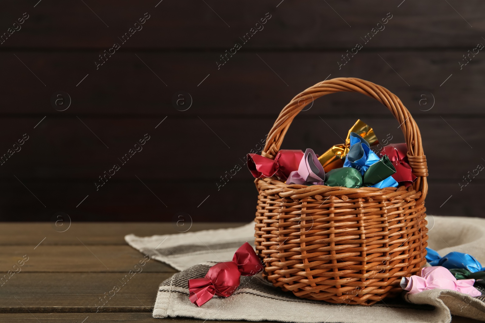 Photo of Candies in colorful wrappers on wooden table, space for text