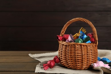 Photo of Candies in colorful wrappers on wooden table, space for text