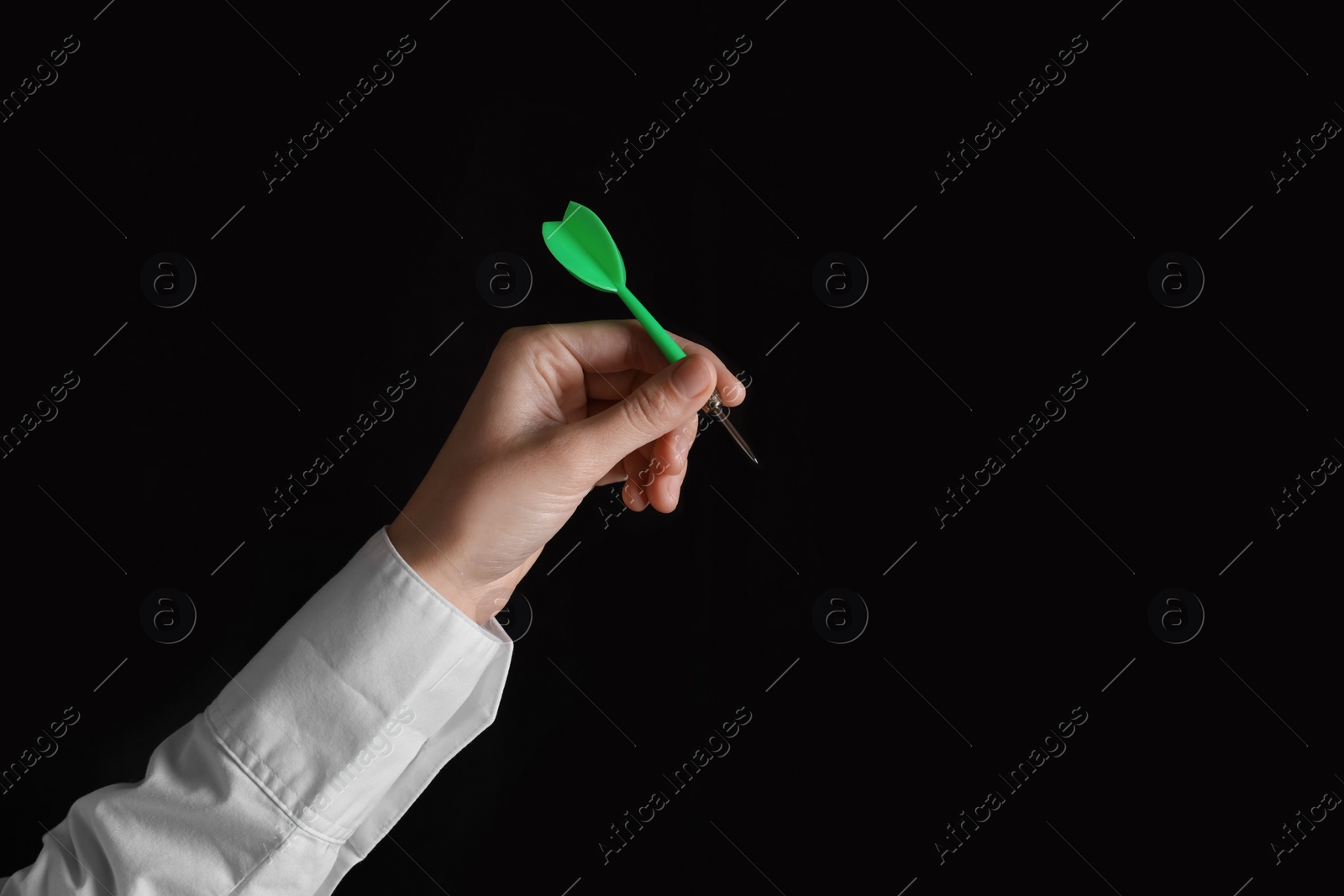 Photo of Businesswoman holding green dart on black background, closeup. Space for text