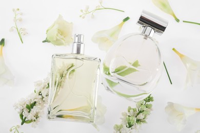 Photo of Luxury perfumes on spring floral decor, top view