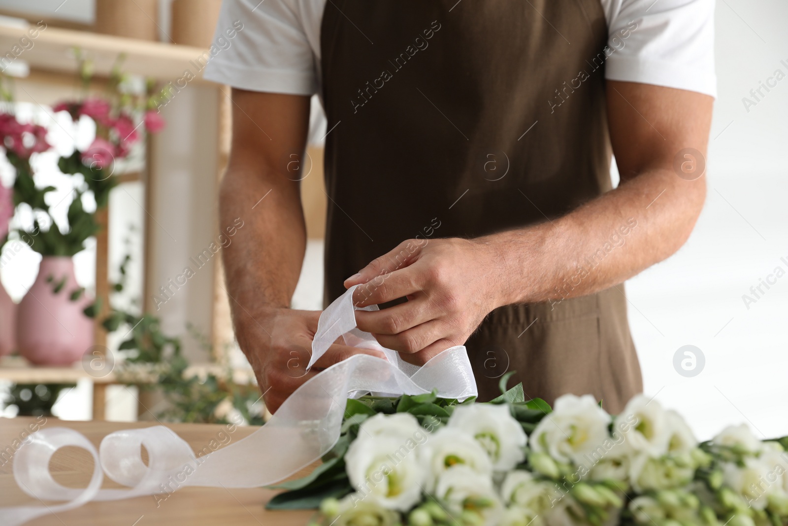 Photo of Florist making beautiful bouquet at table in workshop, closeup