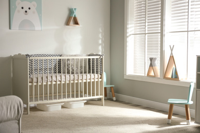 Photo of Cute baby room interior with crib and decor elements