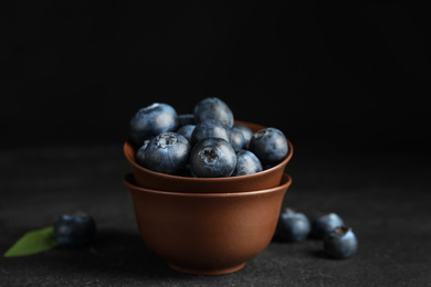 Fresh ripe blueberries in bowl on dark table