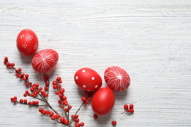 Flat lay composition with painted Easter eggs on wooden table, space for text