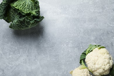 Photo of Fresh ripe savoy cabbage and cauliflower on grey table, flat lay. Space for text