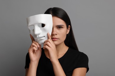 Photo of Multiple personality concept. Woman with mask on grey background