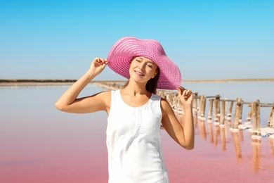 Photo of Beautiful woman with hat posing near pink lake on summer day