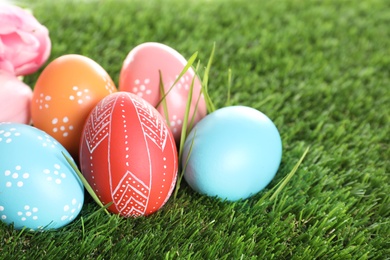 Photo of Colorful painted Easter eggs on green grass, closeup