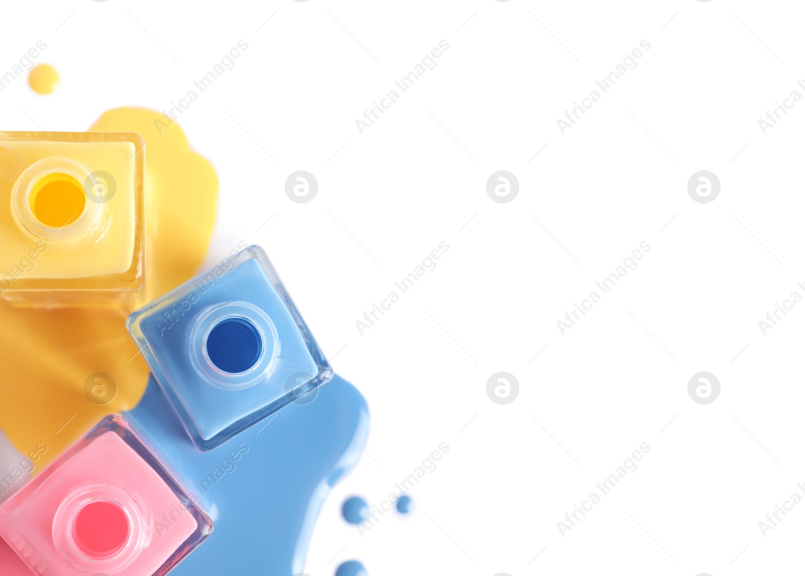 Photo of Spilled different nail polishes with bottles on white background, top view