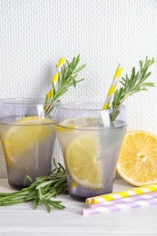 Photo of Tasty refreshing lemon cocktail with rosemary on table