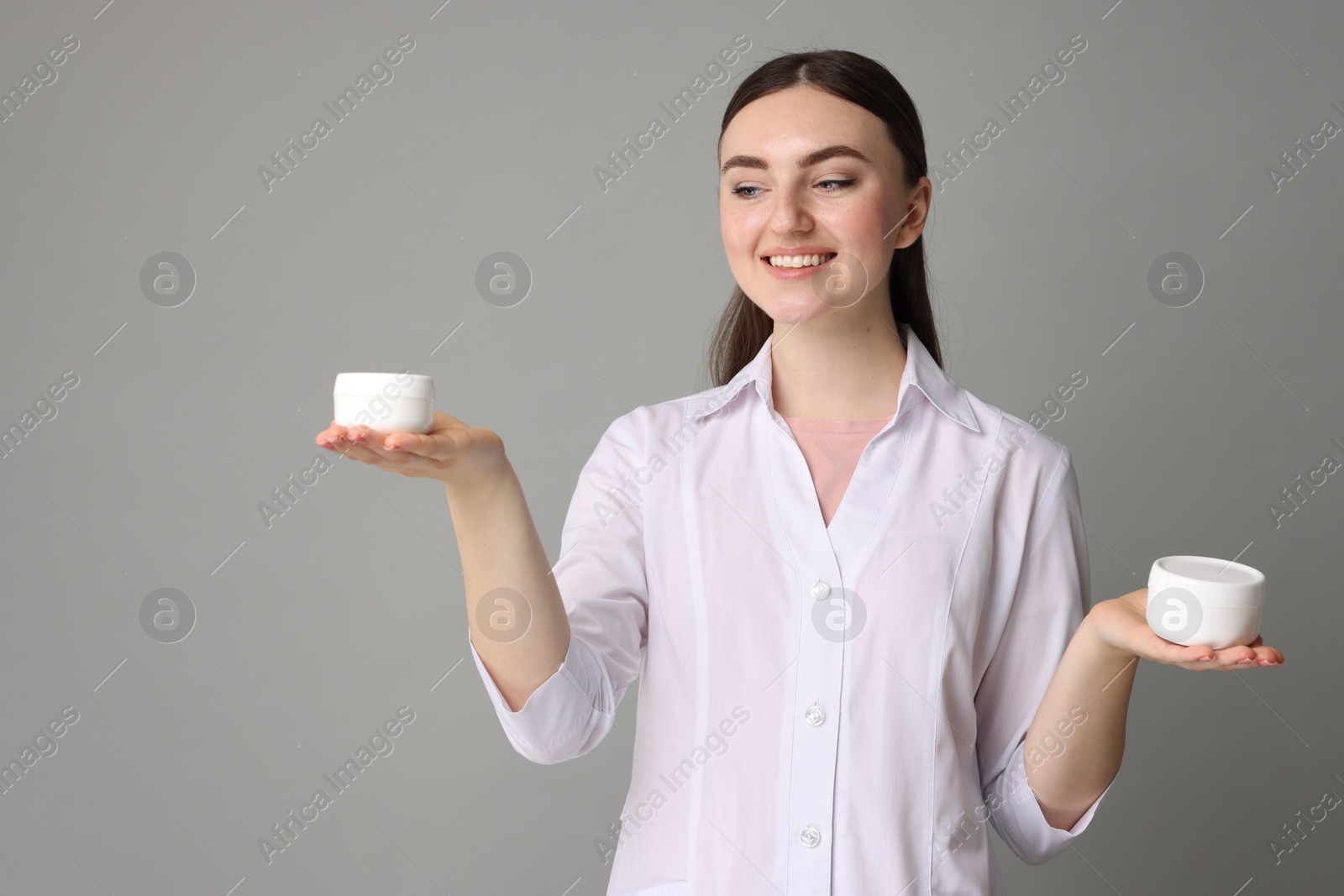 Photo of Cosmetologist with cosmetic products on grey background