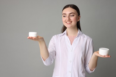 Photo of Cosmetologist with cosmetic products on grey background