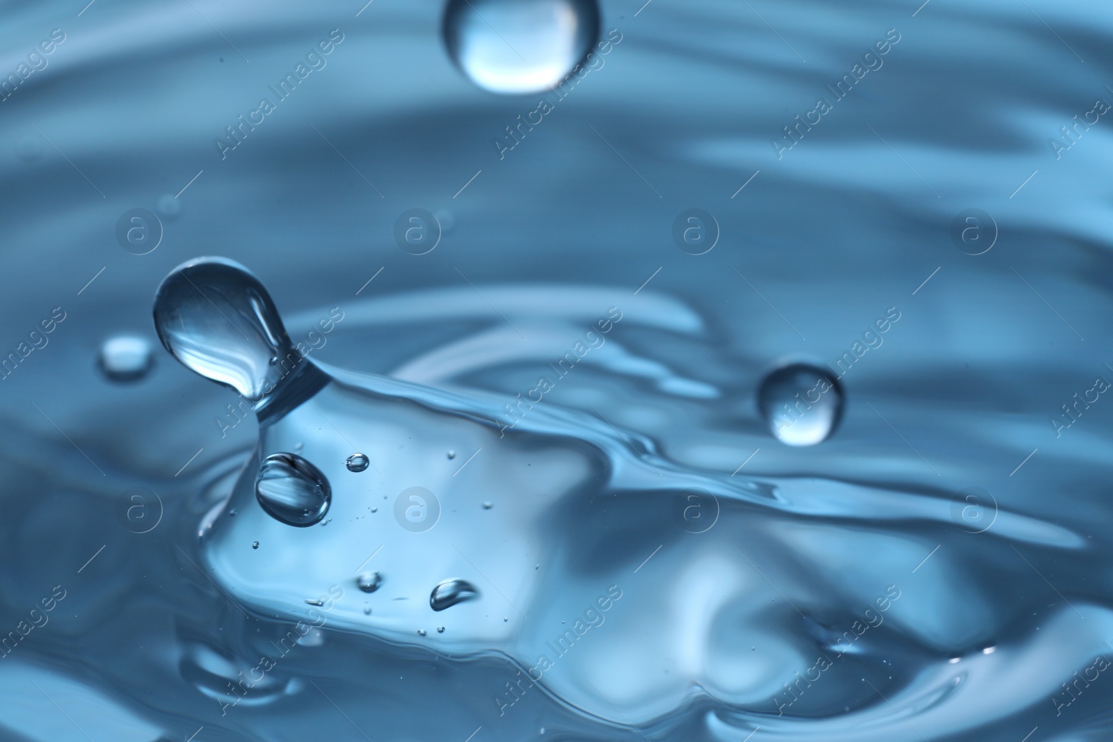 Photo of Drops falling into clear water, closeup view