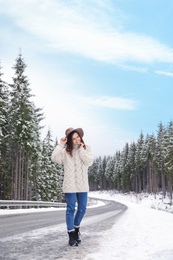 Young woman walking near snowy forest. Winter vacation